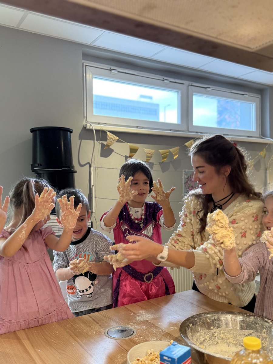 Kinder kneten begeistert Teig und haben Mehl an den Händen